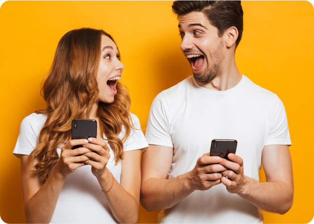 Šťastný mladý muž a žena sa na seba usmievajú, držia v rukách dva smartfóny.